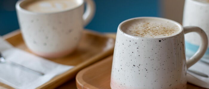 Zwei Keramiktassen mit Kaffee auf Holztabletts, eine mit Schaum und Gewürzen. Bilddatei: dummy.jpg.